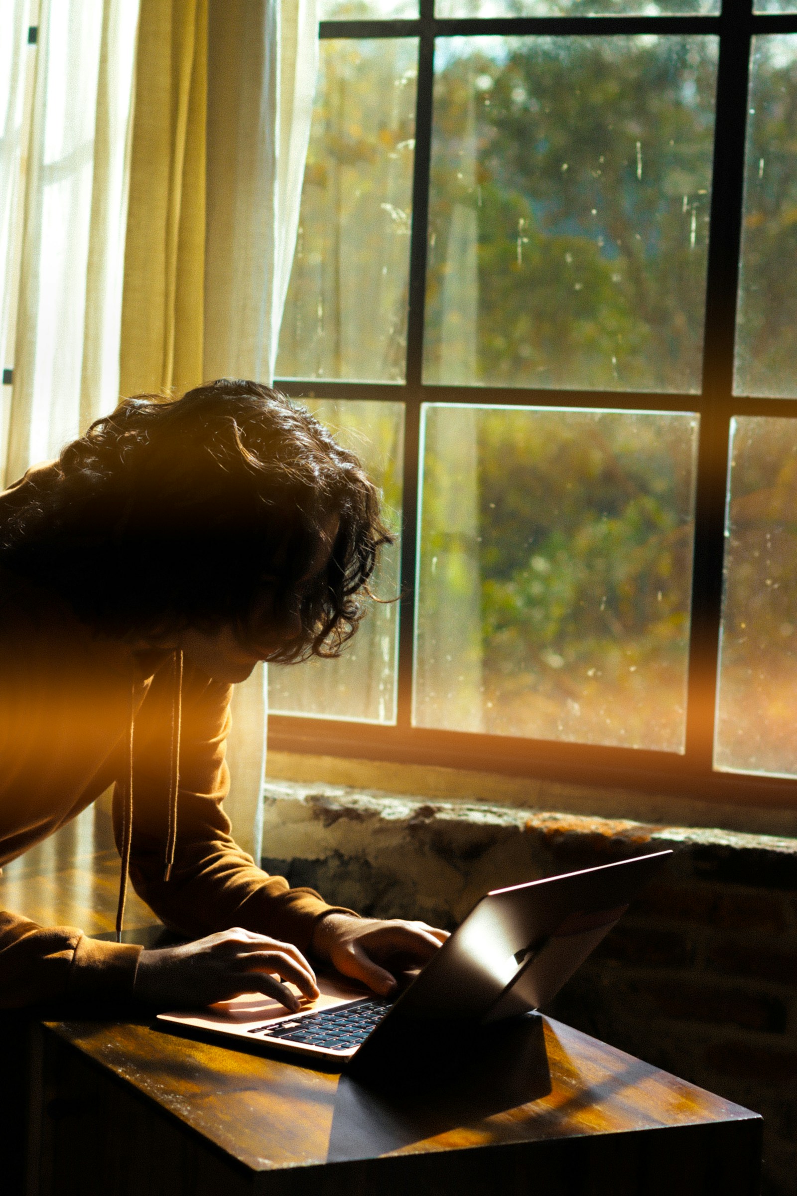 Person working on a laptop by a sunlit window